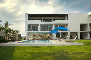 Martínez de La TorreHotel Aqua Spa & Resort的一座带游泳池和两把遮阳伞的大型白色房屋