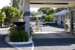 巴瑟尔顿Gale Street Motel & Villas的骑着自行车沿着街道走的女人