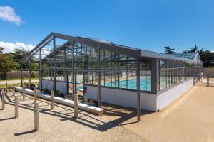 盖朗德Les Cottages de La Baule : Chalet de standing 7 personnes - Piscine的一座玻璃建筑,里面设有游泳池