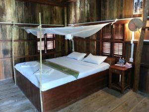 白马市鸟天堂别墅 的一间卧室设有天蓬床和木墙