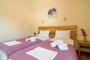 奥林匹亚力神酒店的配有紫色和白色床单的客房内的两张床