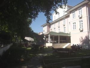 塞尔丘克塞尔丘克乌古拉马奥特里酒店的一座建筑,前面有坐在长椅上的人