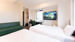 东京Tabist TOKYO CITY VIEW HOTEL的酒店客房设有两张床和一台平面电视。