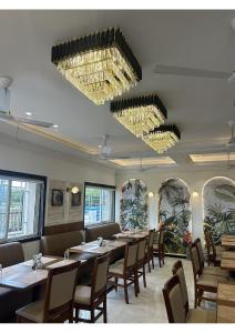 KāgalHotel Yashraj Executive的用餐室配有桌椅和吊灯。