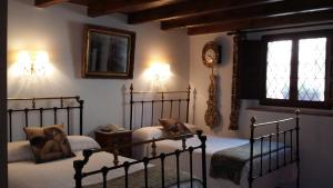 MaderueloHotel Rural El secreto del Castillo的一间卧室设有两张床,墙上挂着一个时钟。