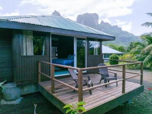 波拉波拉Bora Bora bungalow的木甲板上的房子,配有两把椅子