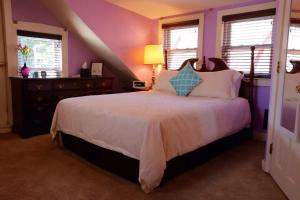 塞伦踏脚石旅馆的一间卧室配有一张紫色墙壁和窗户的床