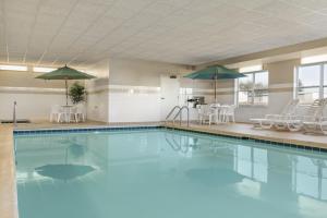 皮奥里亚Country Inn & Suites by Radisson, Peoria North, IL的一个带椅子和遮阳伞的大型游泳池