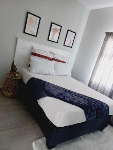 哈博罗内AGM Suites的一间卧室配有白色和蓝色床单