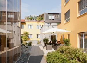 格拉茨Hotel Süd Graz的一座庭院,旁边设有桌子和遮阳伞