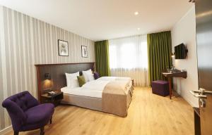 纽伦堡豪瑟精品酒店的酒店客房,配有一张床和两张紫色椅子