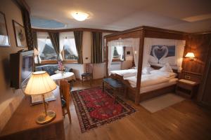 塞尔瓦迪加尔代纳山谷Hotel Garni Concordia - Dolomites Home的一间卧室配有一张天蓬床和一台电视机