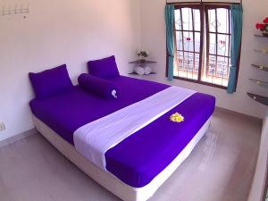 金巴兰全天住宿加早餐旅馆的窗户客房内的大紫色床