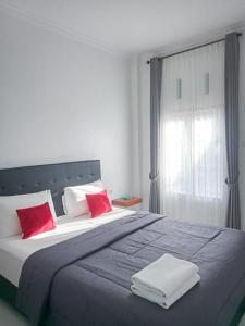 纳闽巴霍Guest House d Valeri的一间卧室配有一张带红色枕头的大床