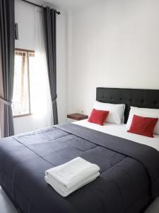 纳闽巴霍Guest House d Valeri的一间卧室配有一张大床和两个红色枕头