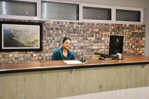 斯瓦科普蒙德Swakopmund Plaza Hotel的坐在砖墙前的柜台上的女人