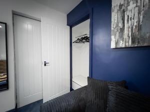 KillingworthNewly Refurbished 6 Person En-suite Apartment Tyne & Wear Newcastle Upon Tyne的一间设有蓝色墙壁和门的卧室