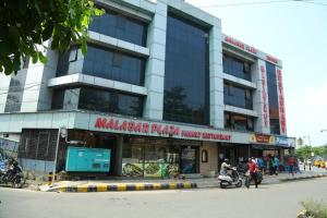 科钦Malabar Plaza DH的街道边的一座建筑,前面的人