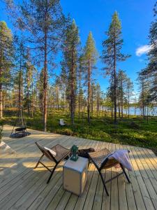 BjörklidenLaplandLiv Glampingtent with private sauna at the lake!的一个带两把椅子和桌子的甲板和树木