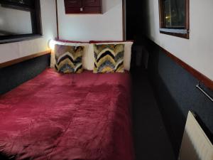 伦敦Comfy Canal Boat in Little Venice by Paddington for Family & Friends的客房内的一张红色床和两个枕头