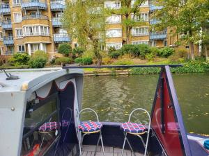 伦敦Comfy Canal Boat in Little Venice by Paddington for Family & Friends的一条河岸边带两把椅子的船