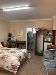 库马ALPINE COUNTRY MOTEL and METRO ROADHOUSE COOMA的一间卧室配有一张床铺和一张桌子,还设有一间厨房