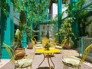雅典ibis Styles Athens Routes的庭院设有黄色桌椅和植物