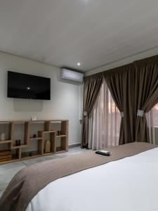 伯诺尼ANEW Hotel & Convention Centre OR Tambo Johannesburg的一间卧室配有一张床和一台平面电视