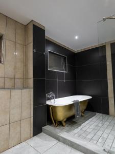 伯诺尼ANEW Hotel & Convention Centre OR Tambo Johannesburg的浴室设有浴缸,铺有黑色瓷砖。