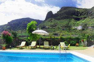 San Juan de la RamblaHoliday Home El Mar的一个带椅子和遮阳伞的游泳池以及山地