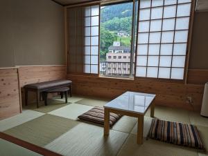 日田市Ryokan Tenryu的一间设有桌子和两个窗户的房间