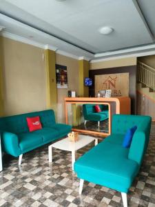 玛琅Noura Guest House Syariah的客厅配有2张蓝色的沙发和1张桌子