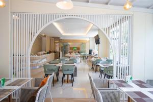 罗勇Phavina Hotel Rayong SHA Extra Plus的拱形用餐室配有桌椅