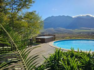 VilliersdorpValley View Eco Country Estate - Paradise in the Winelands的一个带桌子的游泳池,背景是山脉