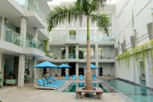 勒吉安AQ-VA Hotel & Villas Seminyak的棕榈树、椅子和游泳池的酒店