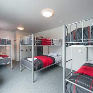 珀斯Wallaby Backpackers Hostel Perth - note - Valid passport required to check in -的一间卧室配有三张双层床,铺有红色床单