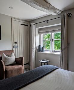 Quenington守护者臂弯宾馆的卧室配有床、椅子和窗户。