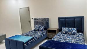 伊斯兰堡Comfy stays near Islamabad airport的一间卧室配有两张带蓝色床罩和椅子的床