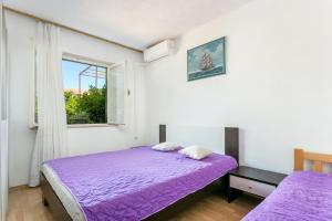 苏佩塔尔Apartments and rooms with parking space Supetar, Brac - 5658的一间卧室设有紫色的床和窗户