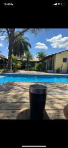 圣湖镇Casa do ipê的坐在游泳池旁的桌子上,坐在咖啡杯上