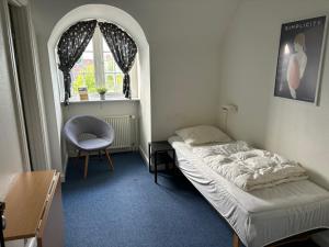 欧登塞欧登塞市丹恩旅馆的卧室配有床、椅子和窗户。