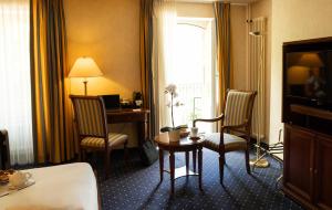 伊韦尔东Grand Hotel et Centre Thermal d'Yverdon-les-Bains的酒店客房配有桌椅,