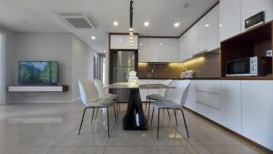 胡志明市Vinh Hoi Apartments - Luxury Apartment Furnished Suites的厨房配有桌子和一些白色的椅子