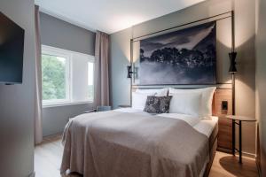 卑尔根爱德华格里格品质酒店的卧室配有一张大床,墙上挂有绘画作品