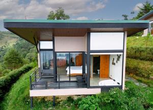 DivisiónVillas Páramo Cloud Forest Hotel的山丘上带绿色屋顶的房子