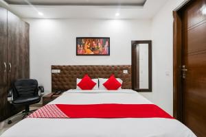 新德里Hotel O Premium Rooms Chhatarpur的一间卧室配有一张带红色枕头的大床