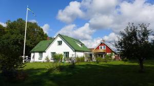 BolestadLilla Trulla Gårdshotell - Feels like home的白色的房子,有绿色的屋顶和红色的房子