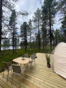 BjörklidenLaplandLiv Glampingtent with private sauna at the lake!的木制甲板配有桌椅和帐篷