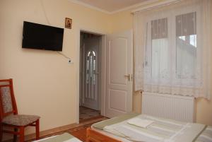 考波什堡Zöldike Vendégház的一间卧室配有一张床,墙上配有电视