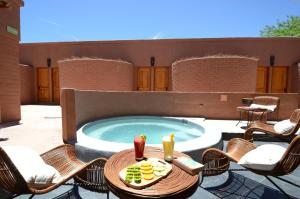 圣佩德罗·德·阿塔卡马帕斯夸尔安迪诺酒店的庭院设有带椅子的游泳池、桌子和饮料